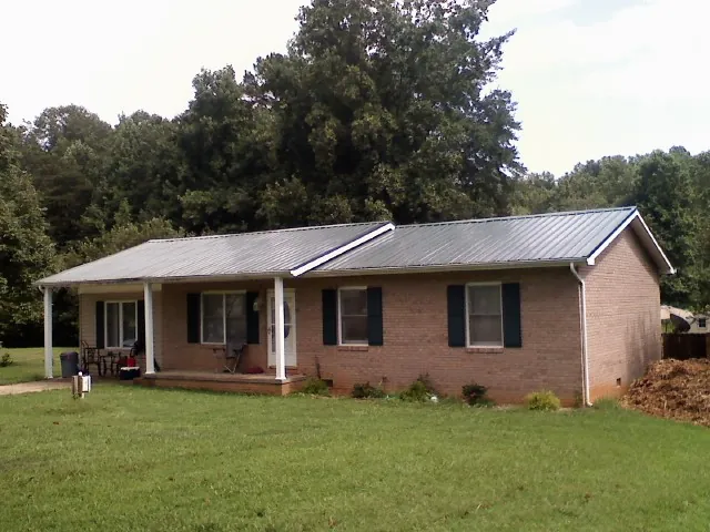 Gray metal roof on a brick ranch house with a side carport in Woodstown