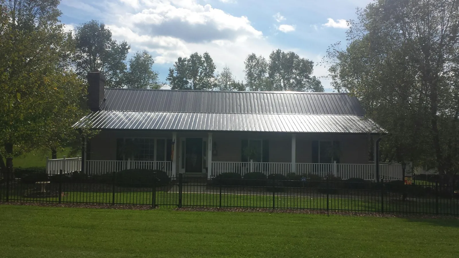 Gray metal roof on a brick ranch with a full width front porch — Gutter Guard Installation work by our crew in Woodstown