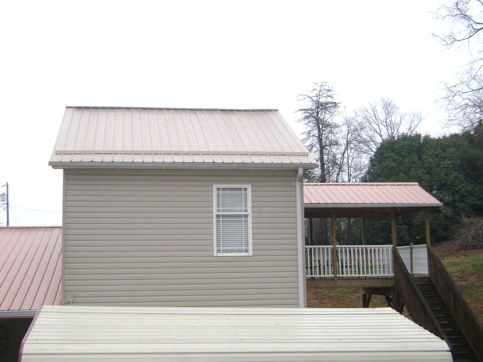 Tan metal roofs on a two story addition and attached porch, from a Roof Replacement job in Woodstown