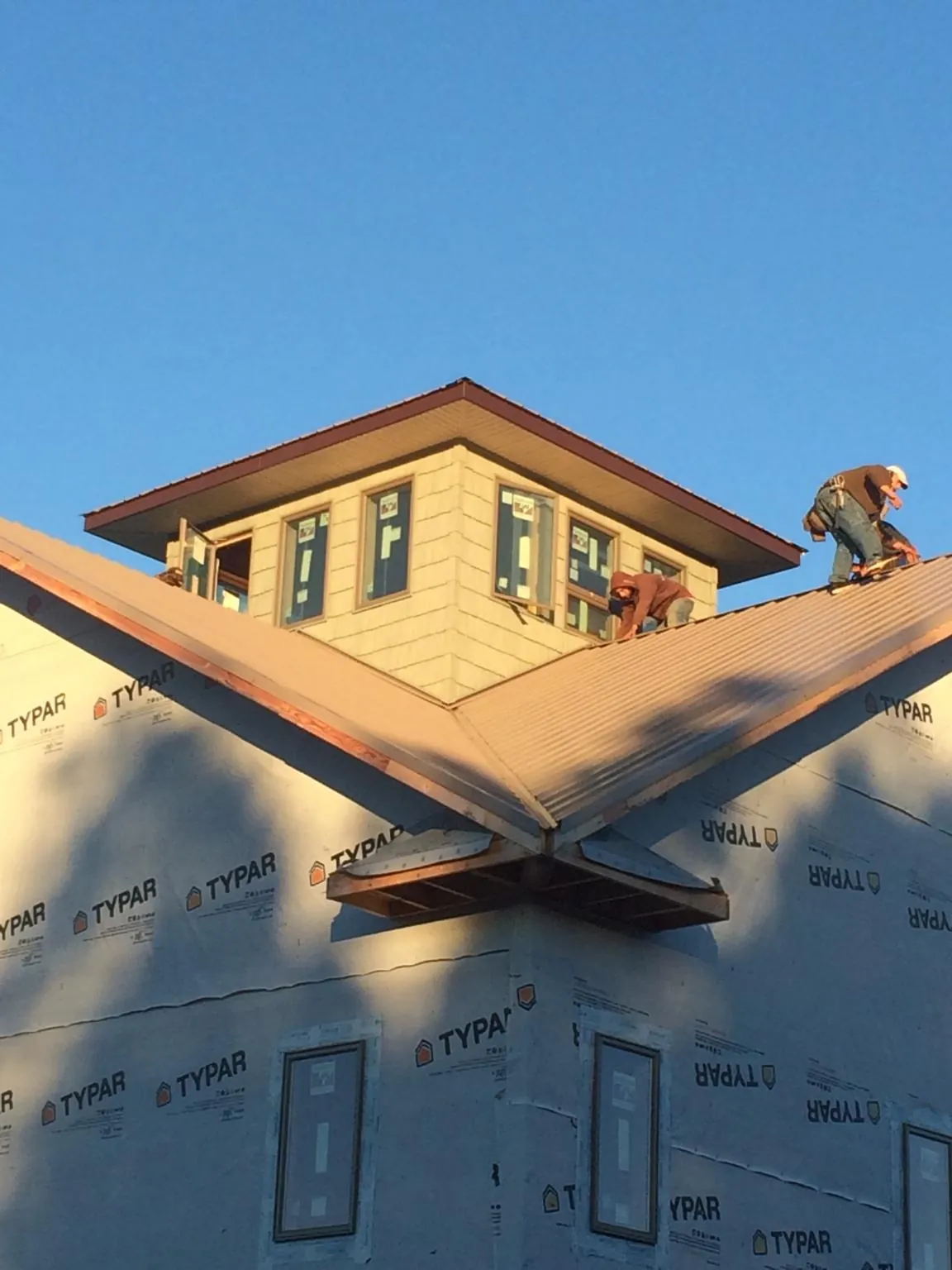 Roofers working around a rooftop cupola on a new metal roof at sunset — Roof Waterproofing in Woodstown by Roofing Brothers